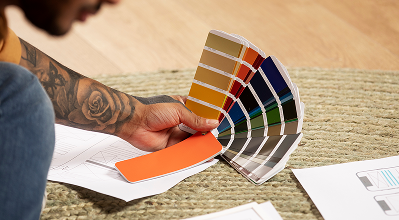 Hand holding a Pantone color fan against fabric swatches