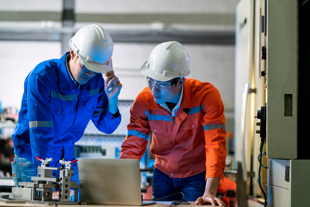 Two U-Lik engineers reviewing a CNC machining process on the factory floor